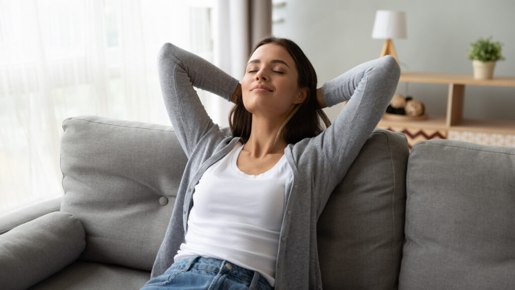 Relaxed serene young woman lounge on comfortable sofa at home stock photo