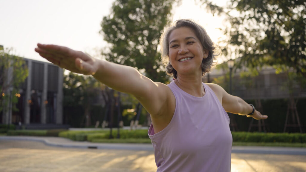Asia adult aged people middle age mindful happy old woman yoga body pose zen calm stress relief outdoor nature public park sun light self love relax elder aging life asian female mental health care.